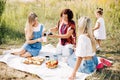 Three generations of women of the same family on a picnic, a grandmother pours tea from a thermos to her daughters and Royalty Free Stock Photo