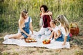 Three generations of women of the same family on a picnic, a grandmother pours tea from a thermos to her daughters and Royalty Free Stock Photo