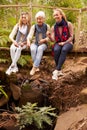 Three generations of women sitting on a bridge in a forest Royalty Free Stock Photo
