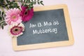 Three gerbera flowers on a writing chalkboard, german text Am 13