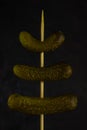 Three gherkins on a skewer, on a dark background Royalty Free Stock Photo