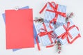 Three gift boxes in a blue stripe with red ribbons, fir branches and a blank sheet of paper lie on a white Royalty Free Stock Photo