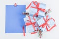 Three gift boxes in a blue stripe with red ribbons, fir branches and a blank sheet of paper lie on a white Royalty Free Stock Photo