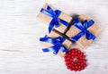 Three gift boxes made of kraft paper with blue ribbons and red coral beads. Gift boxes on a white background. Copy space Royalty Free Stock Photo