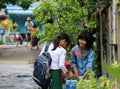 Three girl students in Myanmarese uniform of school white shirt and green Long Yi Discuss the subject of homework.