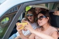 Three girlfriends go on a road trip and take a selfie on a smartphone. The woman is sitting in the car and taking Royalty Free Stock Photo