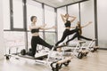 Three girls in a bright gym stretching with equipment