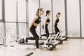 Three girls in a bright gym synchronously stretching with equipment