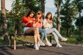 Three girls chatting with their smartphones at the park. Gen Z young girl friends using gadget and having fun outdoors