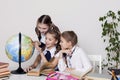 Three girls in the classroom studying geography globe of planet Earth