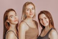 Three girls in comfortable home clothes together on a pink background. Women smile and have fun. The concept of spa treatments,