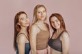 Three girls in comfortable home clothes together on a pink background. Women smile and have fun. The concept of spa treatments,