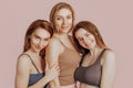 Three girls in comfortable home clothes together on a pink background. Women smile and have fun. The concept of spa treatments,