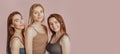 Three girls in comfortable home clothes together on a pink background. Women smile and have fun. The concept of spa treatments,