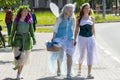 Three girls in fairies costumes, animators at a children`s party are walking along the road in the city,