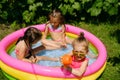 Three girls are having fun in inflatable swimming pool in the garden Royalty Free Stock Photo