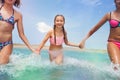 Three girls holding hands running into the sea Royalty Free Stock Photo