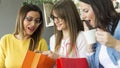 Three girls look in the bag what they bought in the shopping