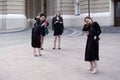 Three girls making photos with smartphone of their friend girl in black dresses