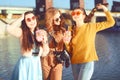 =Three girls near the river against the sky having fun. Fashion girls in sunglasses. Jump, rejoice, drink drinks, smile have fun Royalty Free Stock Photo