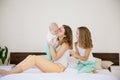 Three girls play sisters in the morning on the bed in the bedroom Royalty Free Stock Photo