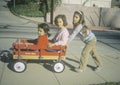 Three girls playing with a red wagon in Glendale, CA Royalty Free Stock Photo