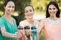 Three girls posing in the park putting forward their hands with sports bottles