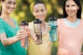 Three girls posing in the park putting forward their hands with sports bottles