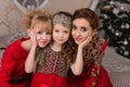 Three girls in a red evening dress the Christmas tree. Royalty Free Stock Photo