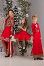 Three girls in a red evening dress the Christmas tree. Royalty Free Stock Photo