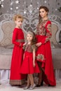 Three girls in a red evening dress the Christmas tree. Royalty Free Stock Photo