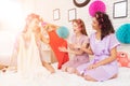 Three girls with curlers in their hair coosing between two dresses. They are celebrating women`s day March 8. Royalty Free Stock Photo