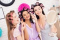 Three girls with curlers in their hair doing make up behind mirror. They are celebrating women`s day March 8. Royalty Free Stock Photo