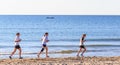 Three girls run on the beach