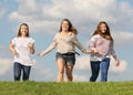 Three girls run at grass and smile Royalty Free Stock Photo