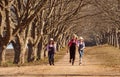 Three girls sisters running skipping down tree lined dirt road Royalty Free Stock Photo