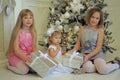 Three girls sisters sitting at the Christmas tree Royalty Free Stock Photo