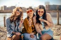 Three girls sit on the beach , near the river, talk, gossip, joke, laugh, smile at womans day. Girls on a hot day eat ice cream.