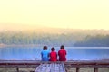 Three girls sitting on a bridge near the lake. Royalty Free Stock Photo