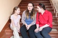 Three girls sitting together on stairs at school,