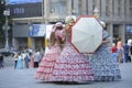 Three girls street vendors wearing bright vintage dresses umbrella standing on a street