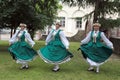 Three girls in traditional dress dancing in the grass