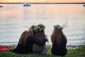Three girls with wreaths of wild flowers by the lake. An evening at Saint John`s Eve by the lake