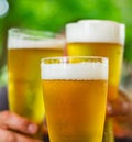 Three glass of beer in hand. Beer glasses clinking at outdoor bar or pub Royalty Free Stock Photo