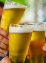 Three glass of beer in hand. Beer glasses clinking at outdoor bar or pub Royalty Free Stock Photo