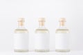Three glass bottles for cosmetic, perfume, alcohol drink with  white label, cork, yellow liquid  on white background, mock up. Royalty Free Stock Photo