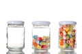 Three glass jar, one empty, one half empty and one full of colored candies isolated on white background with clipping path and cop