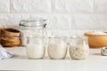 Three glass jars with active sourdough starter. Spelt, rye, and wheat