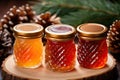 Three glass jars with honey or pine cone jam, surrounded by pine branches on a wooden stand