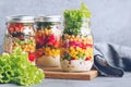 Three glass jars with layering various vegan salads for healthy lunch Royalty Free Stock Photo